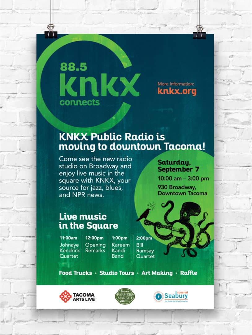 A KNKX poster hung against a white brick wall