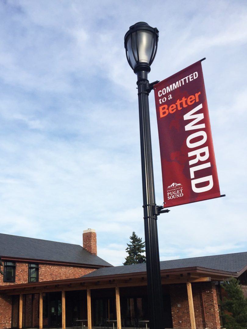 Vertical banner on University of Puget Sound campus reading "Committed to a Better World"