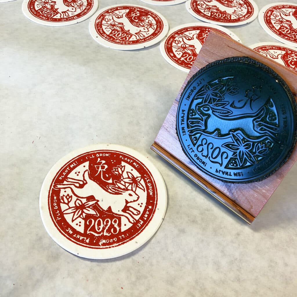 Coasters being rubber stamped with a Year of the Rabbit design in red ink