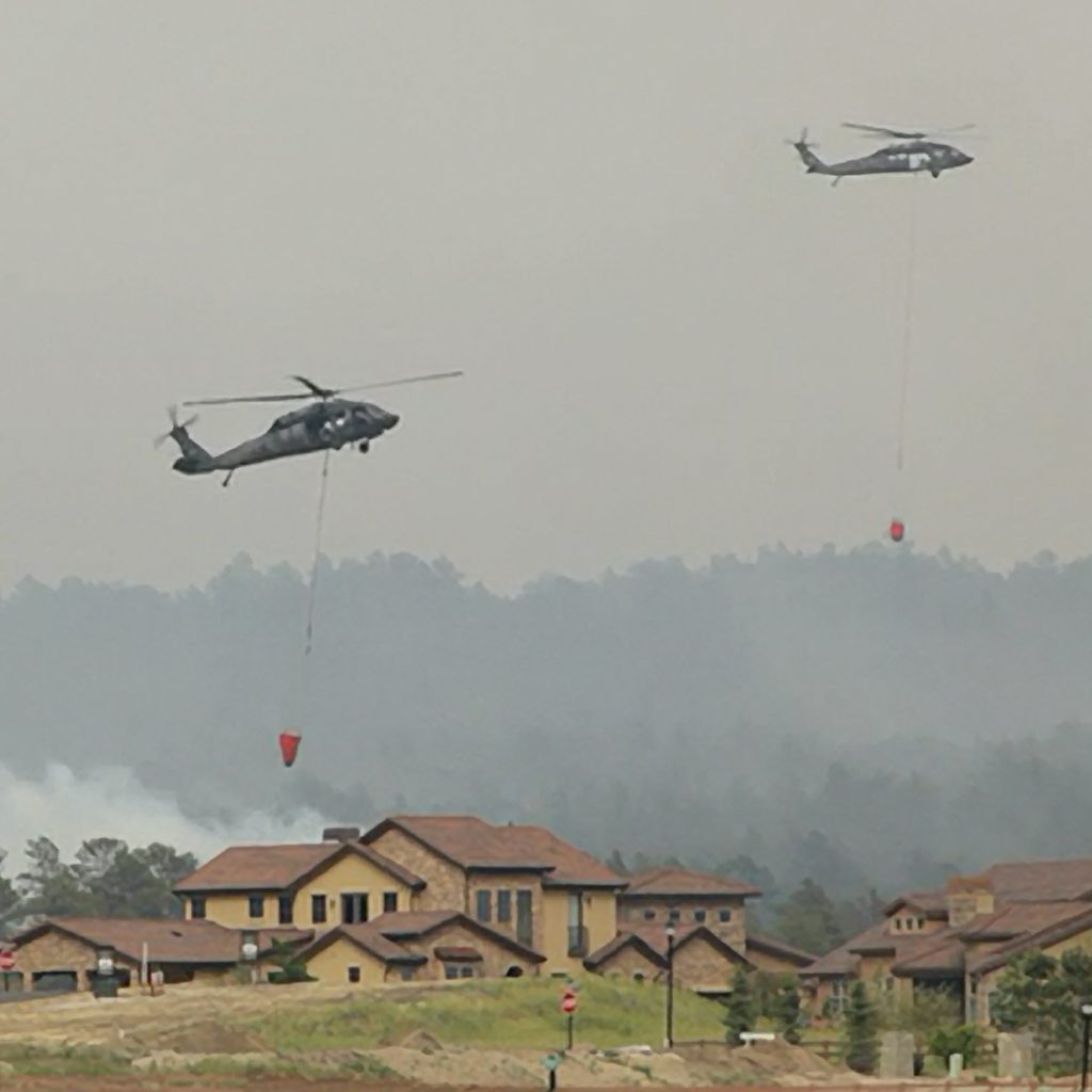 Photo of two helicopters dropping water on an active fire