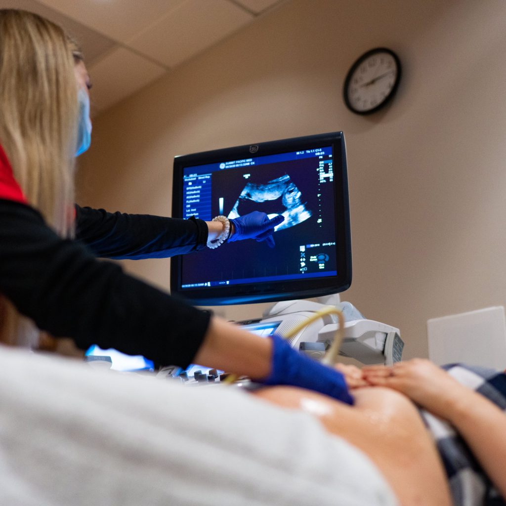 photo of a person laying in a hospital bed and reviewing information with a nurse at Summit Pacific Medical Center