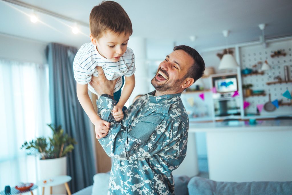 Photo of a father lifting his toddler son in the air for fun