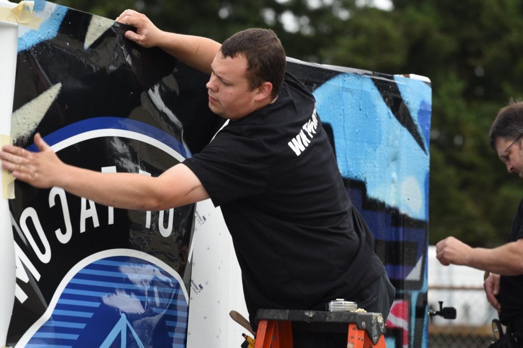 photo of person putting Port of Tacoma wrap on shipping container