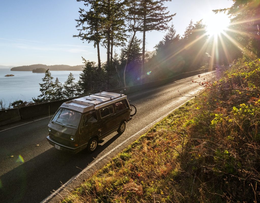 Photo of a Volkswagen Bus driving on a coastal road in Larabee State Park in Whatcom County, Washington