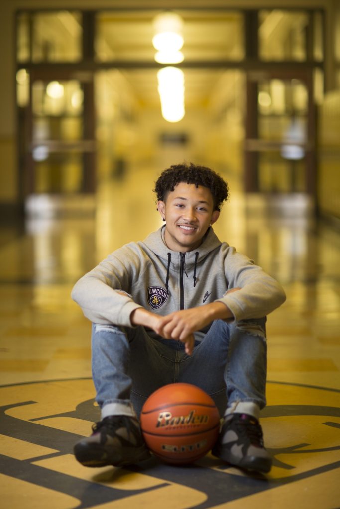 photo of a Tacoma Public Schools student sitting on a gym floor with a basketball in front of them