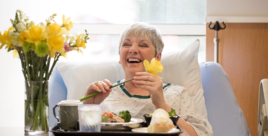 photo of an elderly person laughing and laying in their hospital bed