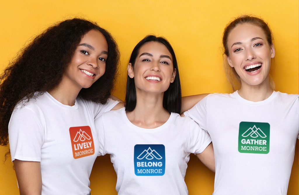 City of Monroe, WA shirt design mockup that shows three women each wearing a different logo design on white t-shirts