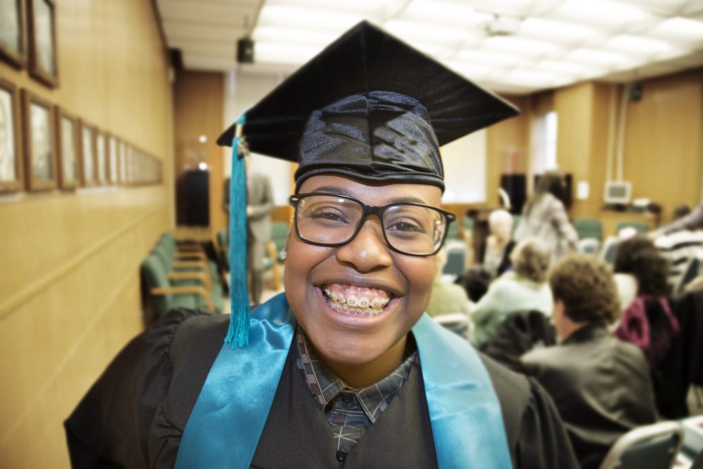 photo of a Tacoma Public Schools student smiling while wearing their graduation cap and gown on