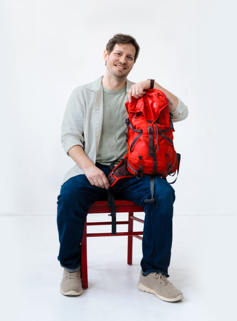 Alex sitting with a red hiking bag