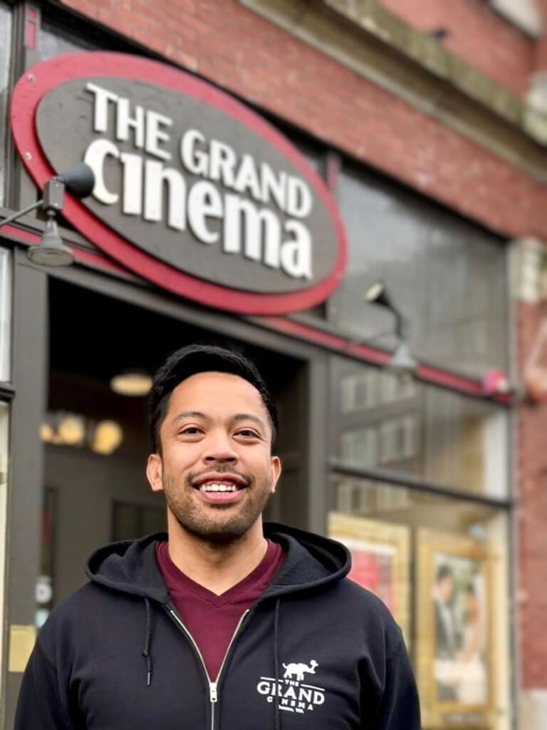Alex Domine poses in front of The Grand Cinema